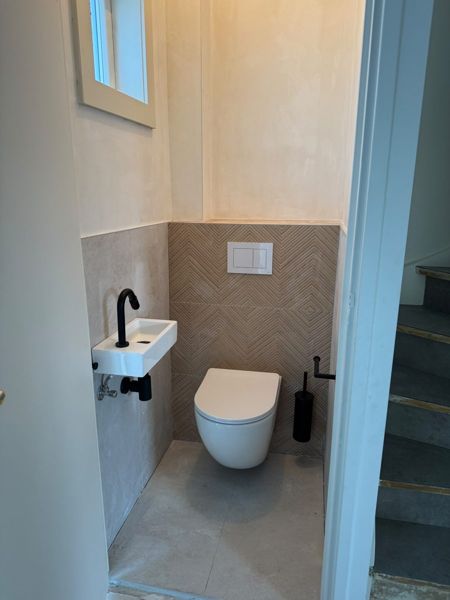 Toilet met visgraattegels, zwart fonteinkraantje en zwart toiletgarnituur