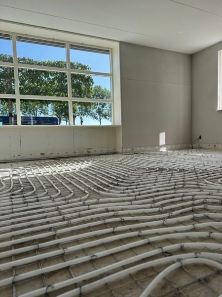 Vloerverwarmingsleidingen gelegd op wapeningsnet in woonkamer