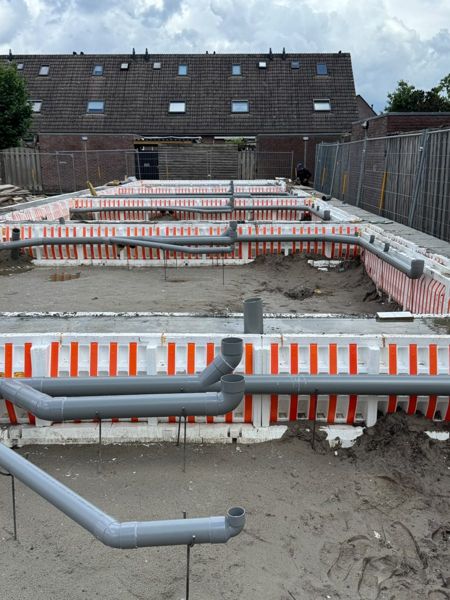 Nieuwe rioolleidingen in de fundering van een woningblok
