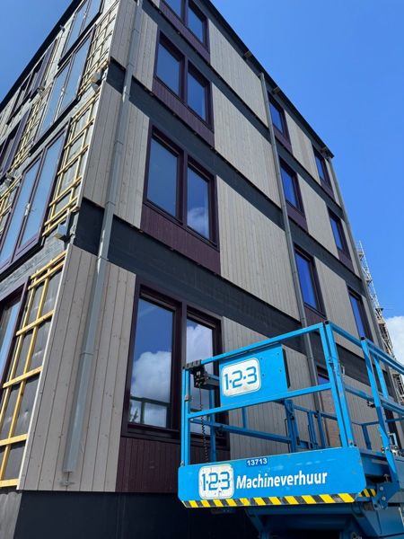 Hemelwaterafvoer gemonteerd op houten gevel van appartementengebouw